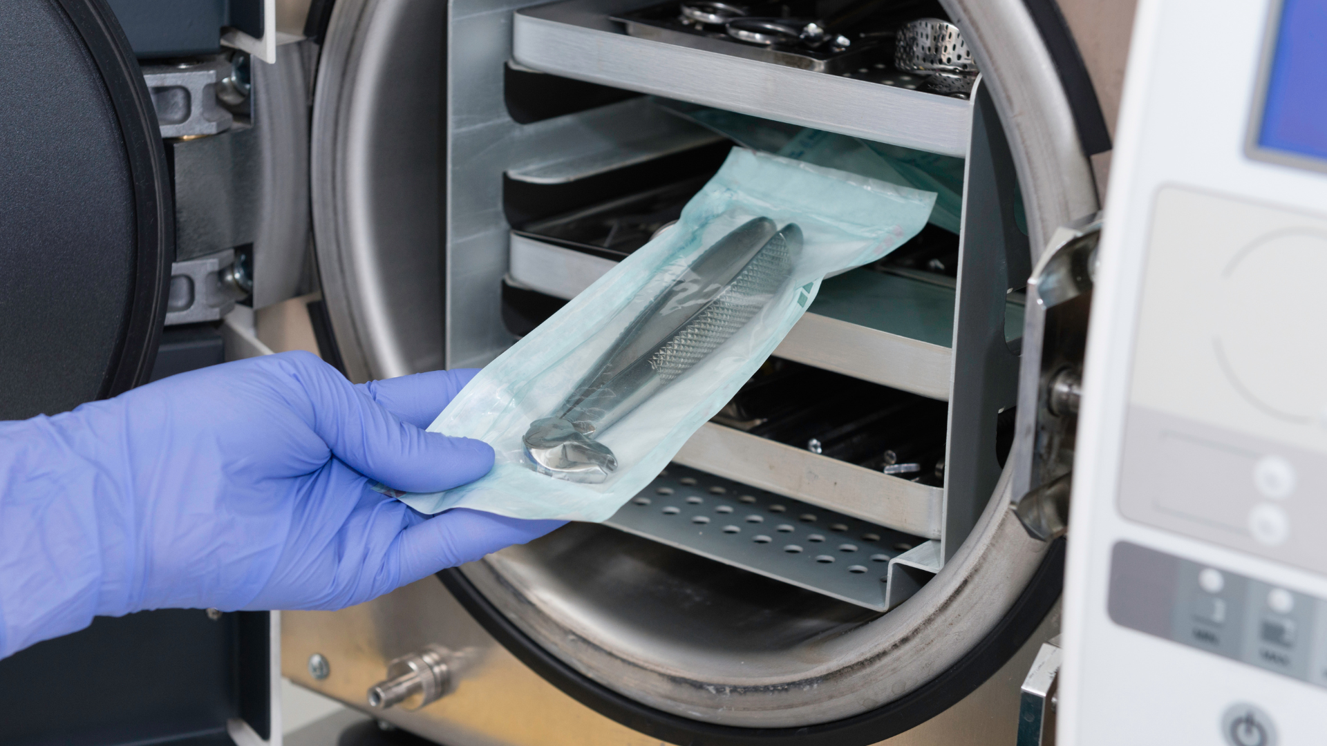 Profissional com luvas retirando instrumento embalado e esterilizado da autoclave
